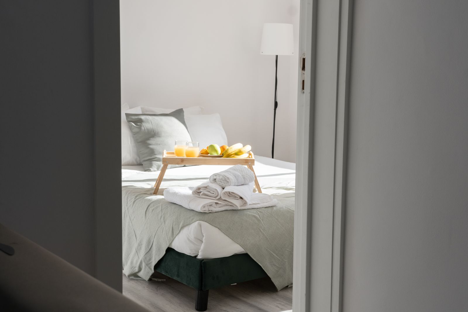 Inviting bedroom with a breakfast tray and fresh towels on the bed, perfect for a relaxing stay.