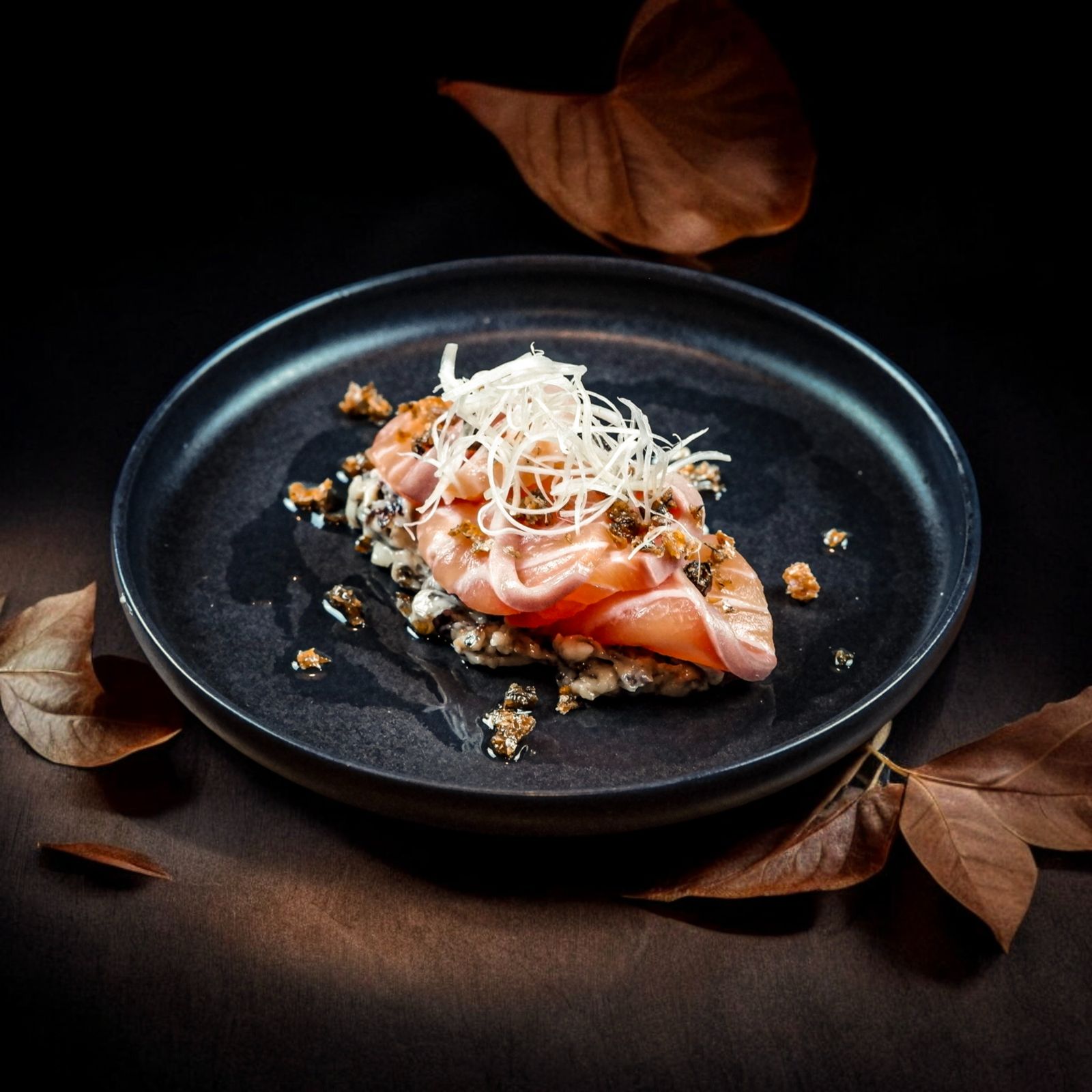 Delicious gourmet salmon sashimi dish elegantly presented on a dark plate.