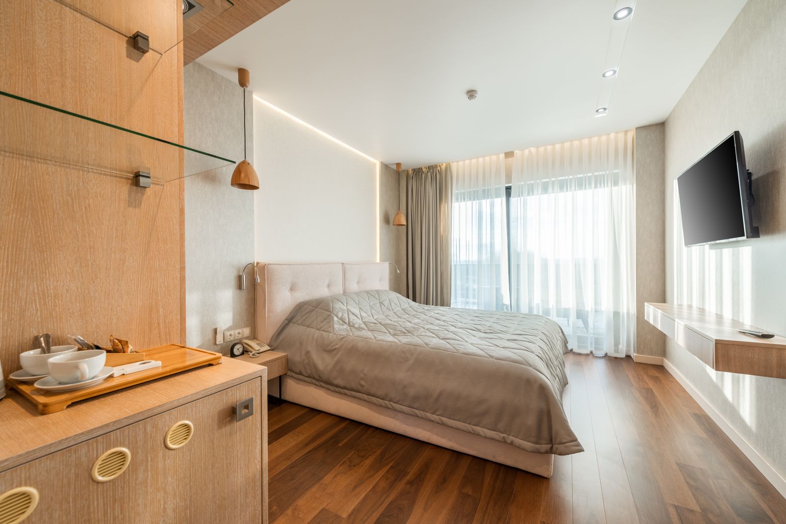 Interior of comfortable bed covered with blanket in bedroom suite in hotel in daylight
