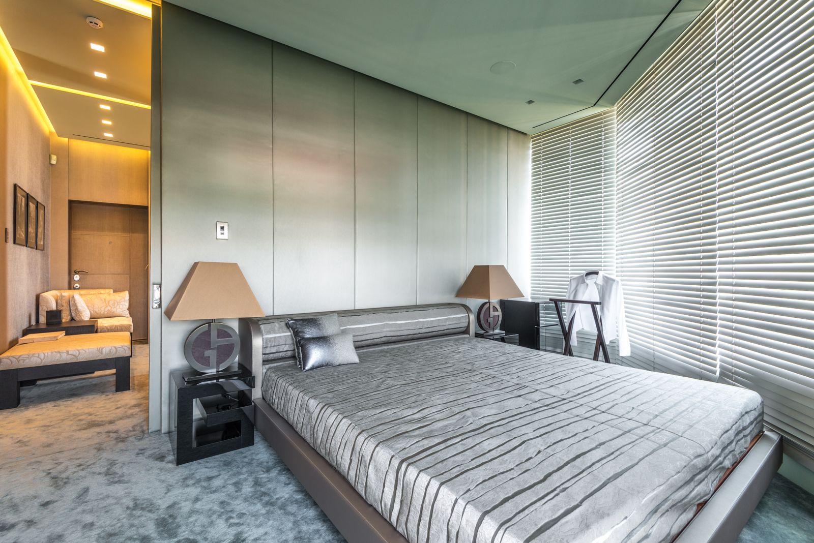 Bright modern bedroom interior with stylish gray decor and natural light filtered through blinds.